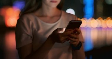 Geceleri, genç bir kız elinde bir akıllı telefon tutar ve ekrana bakar