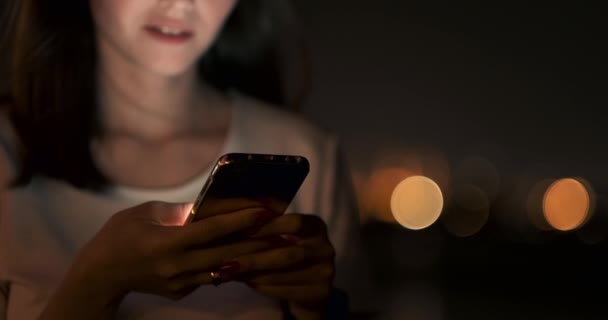 Geceleri, genç bir kız elinde bir akıllı telefon tutar ve ekrana bakar — Stok video