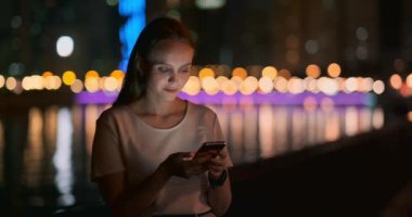 Geceleri, genç bir kız elinde bir akıllı telefon tutar ve ekrana bakar