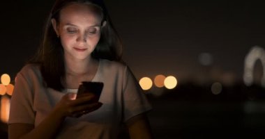 Şehirdeki genç bir kız akıllı telefonuyla mesaj yazıyor.