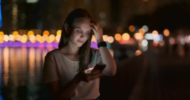 Şehirdeki genç bir kız akıllı telefonuyla mesaj yazıyor.