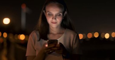 Şehirdeki genç bir kız akıllı telefonuyla mesaj yazıyor.