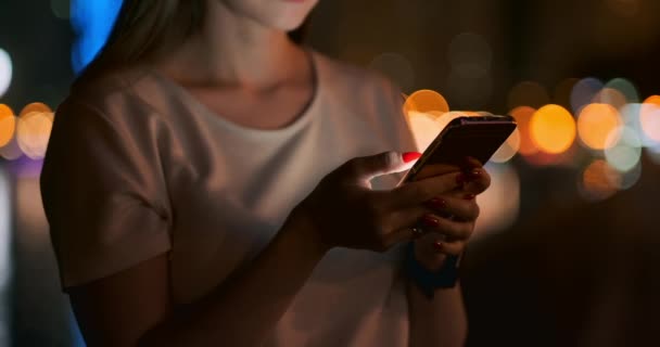 Gros plan d'un téléphone portable entre les mains d'une fille dans la ville la nuit — Video