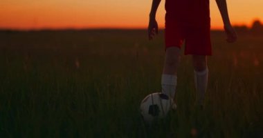 Gün batımında kamerada bir top ile çalışan bir erkek futbolcu izleme