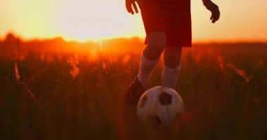 Gün batımında kamerada bir top ile çalışan bir erkek futbolcu izleme
