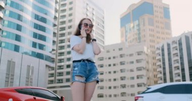 Binaların arkasında telefonla konuşan genç ve güzel bir kadın.