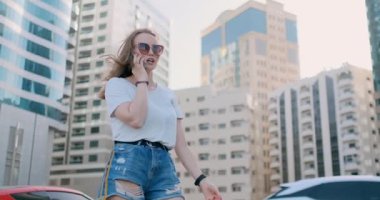 Binaların arkasında telefonla konuşan genç ve güzel bir kadın.