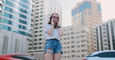 Binaların arkasında telefonla konuşan genç ve güzel bir kadın.