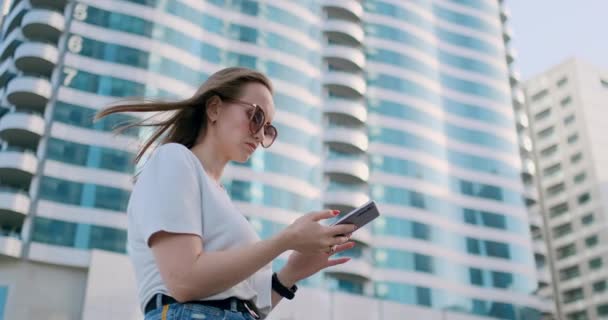 Chica turística en el verano en Dubai escribe un mensaje, mira un mapa en el teléfono inteligente — Vídeos de Stock