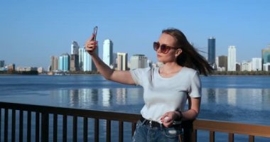 Yaz aylarında, büyük şehrin arka planda ve rıhtımkız akıllı telefon selfie alır
