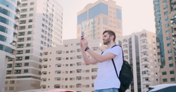 Hombre turista con una mochila toma fotos usando un teléfono inteligente — Vídeos de Stock