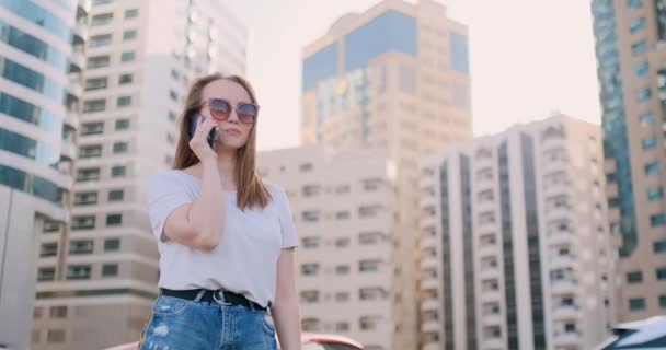 Joven hermosa mujer hablando por teléfono en el fondo de los edificios — Vídeos de Stock