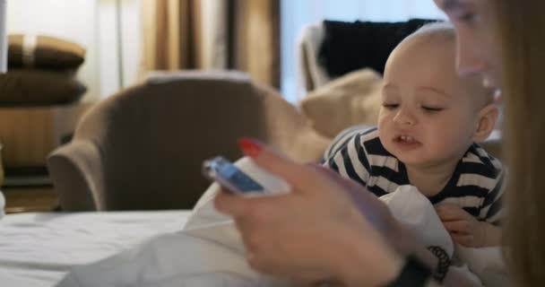 Mamma och barn som ligger på sängen tittar på smartphone skärmen — Stockvideo