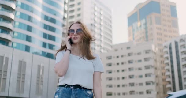 Fiatal gyönyörű nő beszél a telefonon a háttérben az épületek — Stock videók