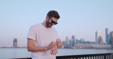 Yazın rıhtımda duran genç bir adam akıllı saat ekranını kullanıyor