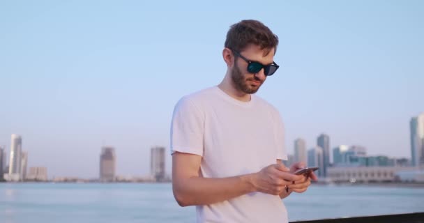 De man belt het nummer op de telefoon en gesprekken op de achtergrond van het panorama van Dubai. Close-up van de hand. — Stockvideo