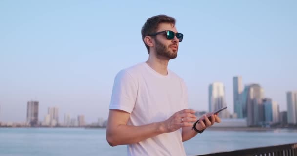 El hombre marca el número por teléfono y habla en el fondo del panorama de Dubai. Primer plano de la mano . — Vídeos de Stock