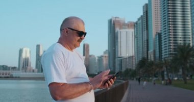 Düşük açılı manzara çekici adam akıllı telefon 4 g Internet iletişim arama arkadaşlarınızla sohbet kullanarak elinde tutan sokak arka plan bulanık. Elektronik kablosuz aygıt kavramı