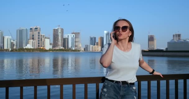 Mladá krásná žena v létě stojí na nábřeží mluvit do telefonu — Stock video