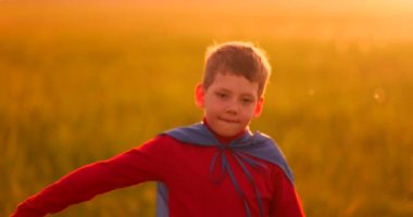 Küçük çocuk oynar ve gün batımında bir süper kahraman hayalleri