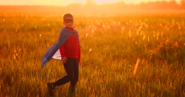 Niño juega y sueña con un súper héroe al atardecer — Vídeo de stock