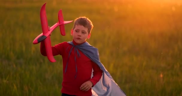 若い男の子のパイロットと日没時にフィールドで実行され、飛行機の夢と遊ぶ — ストック動画
