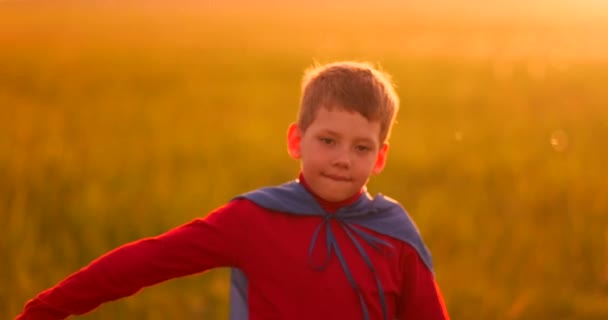 Mały chłopiec gra i marzenia o Super Hero o zachodzie słońca — Wideo stockowe