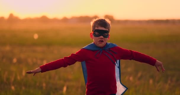 Fiú a szuperhős jelmez-és maszk fut át a területen naplementekor álmodik és fantasizing