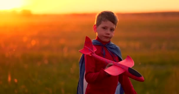 Een kind bij zonsondergang fantasa en verbeeldt zichzelf een piloot bij zonsondergang — Stockvideo