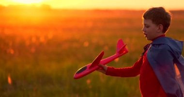Gün batımında elinde bir uçakla sahada oynayan çocuk