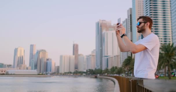 Muž stojící na nábřeží fotografuje na telefonu — Stock video