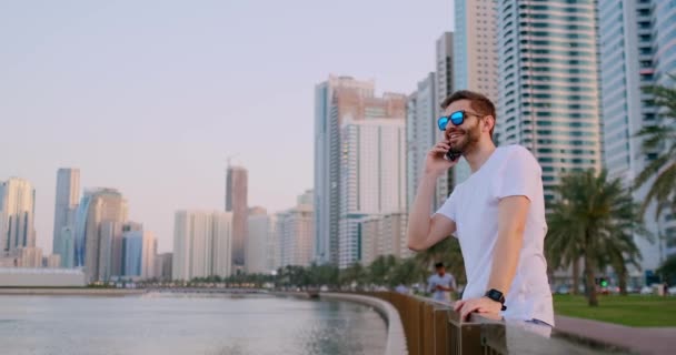 Muž, který stojí na nábřeží a mluví na telefonu a poslouchá — Stock video