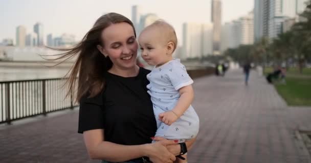 No verão, uma jovem mãe caminhando com uma criança ao longo do passeio — Vídeo de Stock