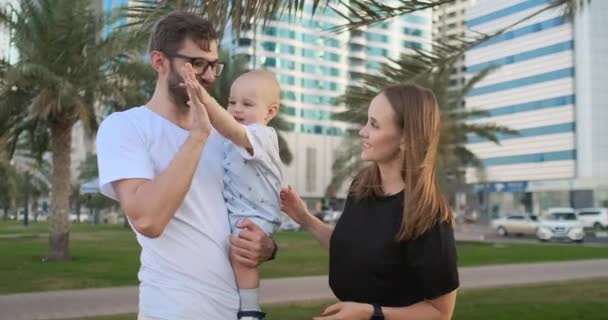 A criança toma a palma da mão do pai sorrindo e rindo de pé no parque de verão — Vídeo de Stock