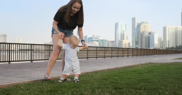 O menino segurando a mão de suas mães dá os primeiros passos — Vídeo de Stock