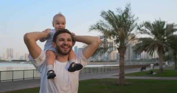 Отец идет с ребенком, сидящим на шее — стоковое видео