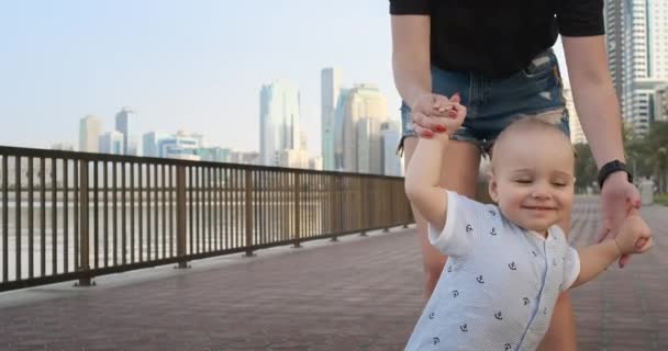Влітку молода мама гуляє з дитиною по набережній — стокове відео