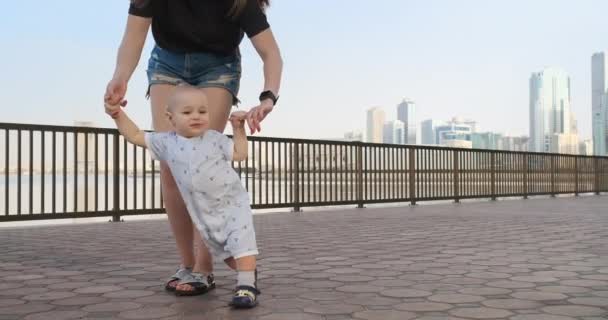 The boy holding his mothers hand makes the first steps — Stock Video