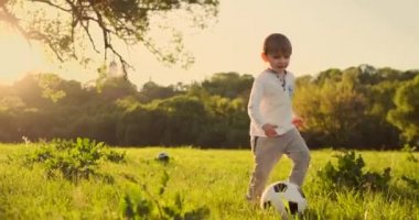 Yaz sahasında gün batımında çalışan futbol topu ile çalışan mutlu çocuk