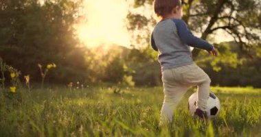 Çocuk çim arka görünümü ile sahada çalışan yaz aylarında bir futbol topu ile ayakta.