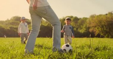 Çayırda futbol oynayan iki oğlu olan baba