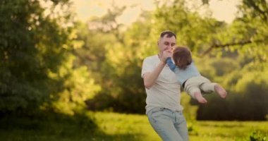 Sevgi dolu baba yavaş hareket yavaş hareket yaz aylarında bir çayırda gün batımında boyun oturan çocuk ile yürürken gülümsüyor