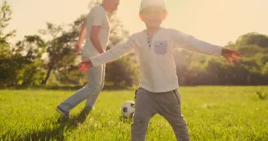 Çayırda futbol oynayan iki oğlu olan baba
