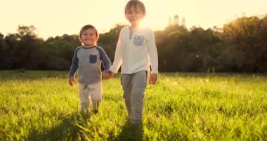 İki kardeş yaz gün batımında mutlu ve neşeli el ele tutuşarak sahada yürümek
