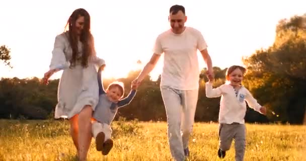 Famille heureuse leur homme avec deux enfants marchant sur le terrain au coucher du soleil dans la lumière du coucher du soleil en été par temps chaud — Video