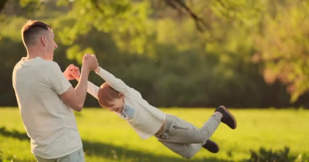 Любящий молодой отец и сын играют на траве летом на закате в замедленной съемке — стоковое видео