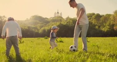 Çayırda futbol oynayan iki oğlu olan baba