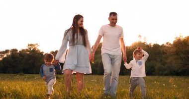 Mutlu aile sıcak havalarda yaz aylarında gün batımıNda gün batımında sahada yürüyen iki çocuklu adam