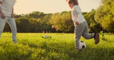 Genç baba ve küçük oğlu futbol sahasında futbol oynuyor..