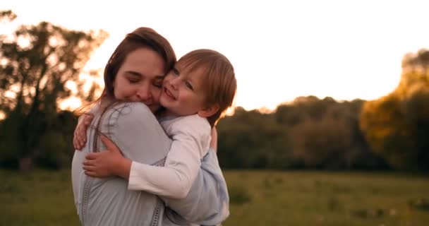 Chłopiec przytulanie matka o zachodzie słońca w lecie, kochający syn i szczęśliwą rodzinę dotykając — Wideo stockowe